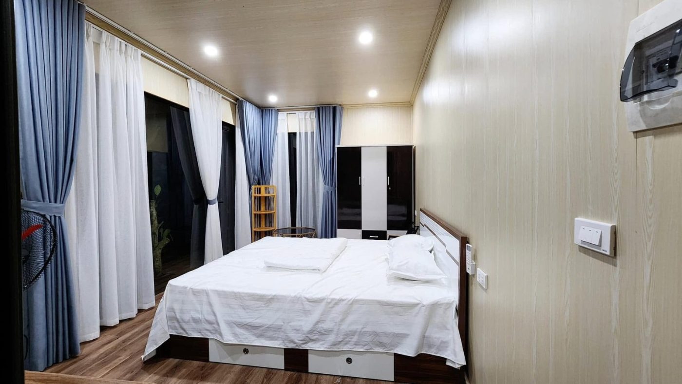 Lối đi vào khuôn viên xanh với mái nhà và dãy núi phía xa